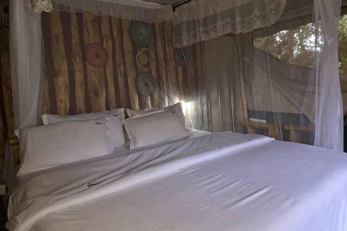 Designed to offer a peaceful, cozy sanctuary after a demanding day of trekking, this budget-friendly eco-accommodation features a spacious, inviting bed dressed in clean, crisp white linens and comfortable pillows. The bed is fully enclosed by a protectiv