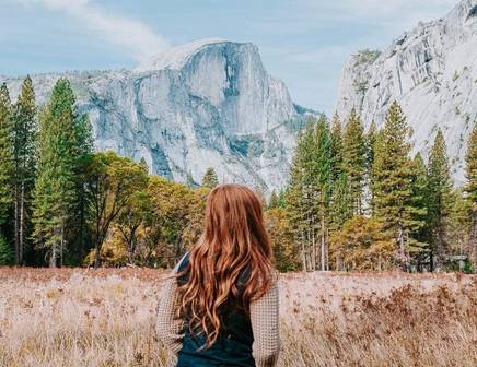 Orange-haired girl gazing at the granite cliffs of Yosemite National Park