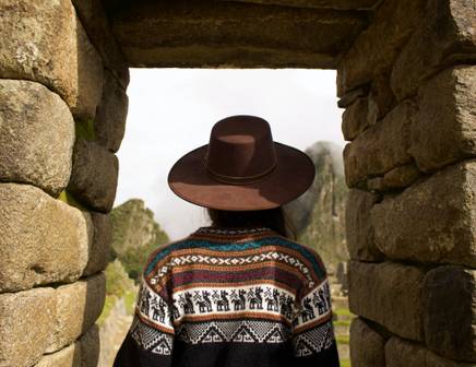 Une femme regardant à travers la Porte du Soleil vers la Citadelle Perdue de Machu Picchu