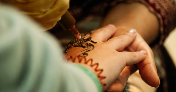 Une femme se faisant tatouer au henné par une artiste mehndi
