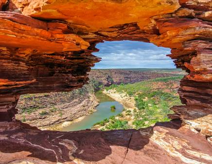 Peeking through a carved out natural window at the dry Australian outback in the Northern Territory