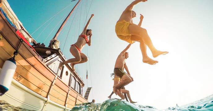 A group of people jumping of a sail boat