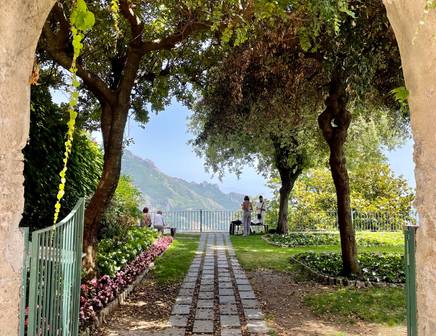 A person looking through a decorated arch onto the shoreline of the Amalfi Coast, Italy