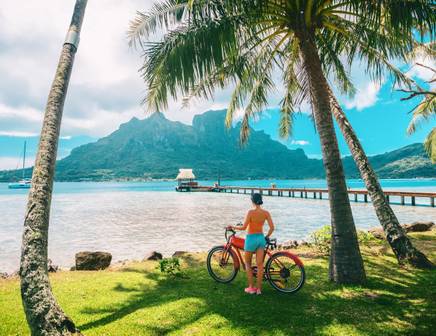 Une femme admirant l'océan à côté de son vélo