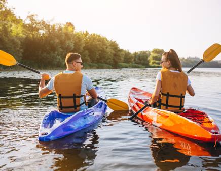 Un homme éclaboussant l'appareil photo avec de l'eau lors d'une aventure active en kayak