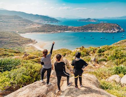 A group of women hiking a mountain overlooking the Vietnam coastline
