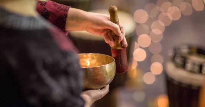 A woman playing a traditional Tibetan singing bowl
