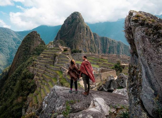 Un homme et une femme devant le Machu Picchu, une ancienne merveille péruvienne.