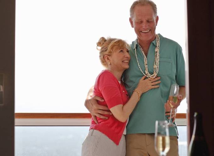 Un couple de seniors sur le pont d'une croisière fluviale, souriant en sirotant une coupe de champag