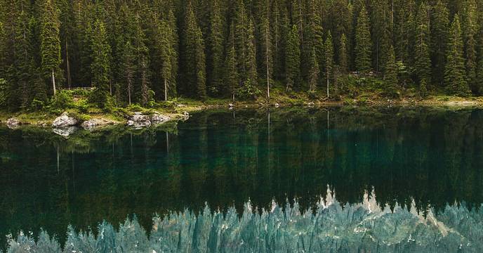Person watching mountains reflected in a lake