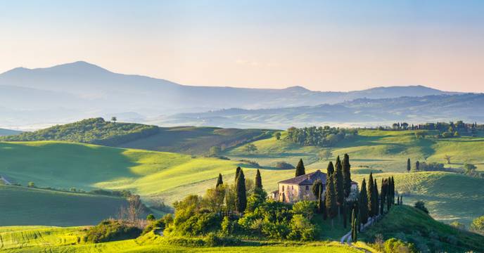 Morning mist over green rolling hills in Tuscany