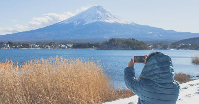 A person taking a picture of Mount Fuji in winter