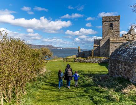 Eine Mutter und ihre beiden Kinder spazieren durch den Schlosspark in Schottland