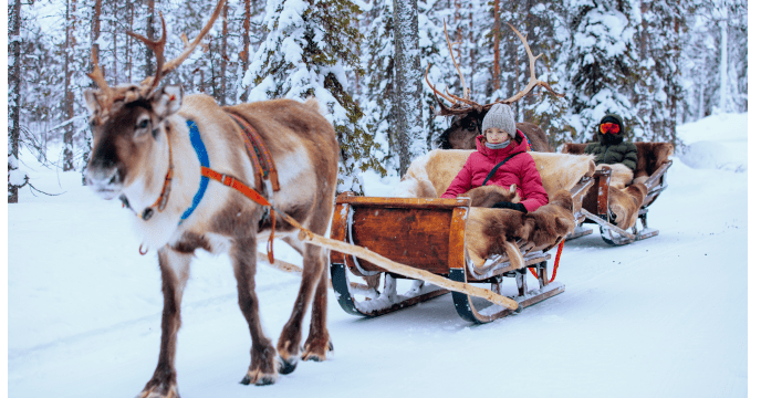 Ein Rentier zieht einen Schlitten mit Kindern darauf in Lappland, Finnland