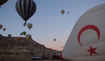Hot air balloons over a rocky landscape with a Turkish flag.