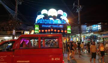 Bustling night market scene with 'Patong Beach' sign lit up.