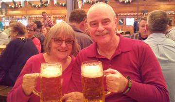 Couple holding large mugs of beer in a festive setting