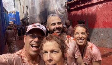 Group selfie during a tomato fight event, all participants are covered in tomatoes.