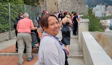Person smiling with a large stone tower and other tourists in the background.