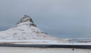 Snow-covered mountain with a clear sky, likely Kirkjufell in Iceland.