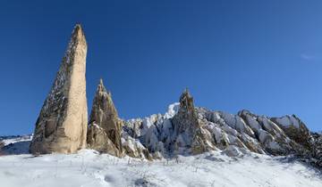 Tall snow-capped rock pillars against a clear blue sky.
