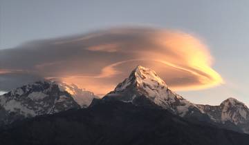Snow-capped mountains with dramatic cloud formations at sunrise.