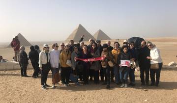 Large group of tourists posing in front of pyramids.