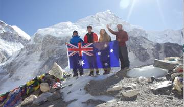 Group holding a flag in front of snowy mountains.