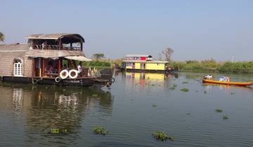 Houseboats on a calm river with small boats.