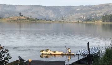 Person paddling a canoe on a tranquil lake.