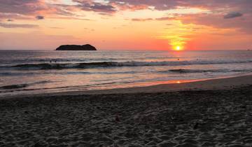 Sunset over the ocean with an island in the distance.