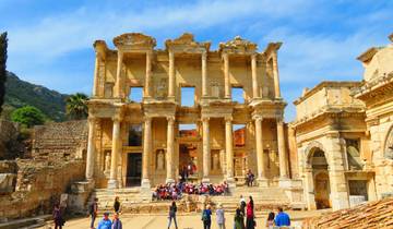 The ancient ruins of a grand building with tourists.