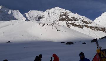 Snowy alpine panorama with people wearing winter clothes in the foreground.