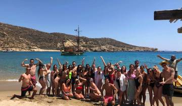 Group of people posing on a beach with a boat and mountains