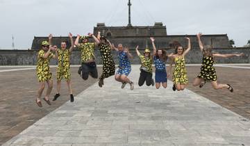 Group jump shot in matching outfits with an ancient fortress in the background.