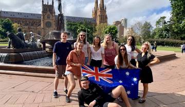 Group of people holding an Australian flag in front of a fountain.
