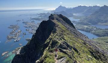Hikers on a rocky mountain trail with a panoramic view of the sea.