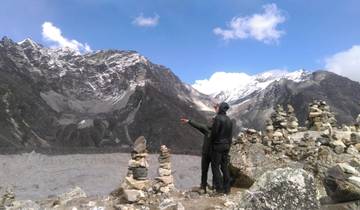 Two hikers pointing towards the mountains in a rocky terrain.