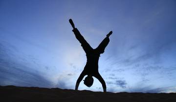 Silhouette of a person doing a handstand at dusk.