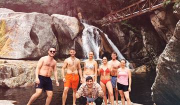 Group of people in swimwear by a waterfall.