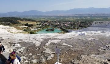 Scenic view of Pamukkale terraces with tourists and mountains.