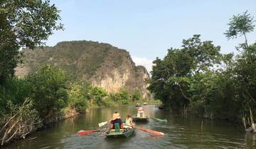 People rowing boats through scenic landscape with cliffs.
