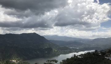 Scenic view of mountains and a river under a cloudy sky.