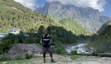 A person standing in front of a mountainous landscape with trees.