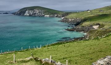 Coastal landscape with green fields and turquoise water.