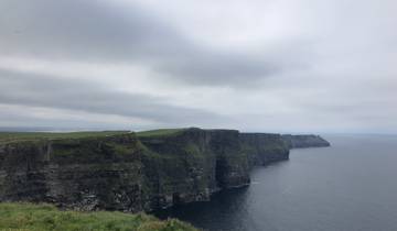 Cliffs overlooking the sea with a cloudy sky.