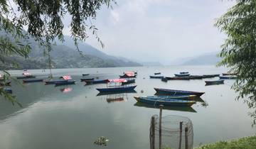Tranquil lake with colorful boats and hills in the background.