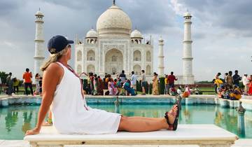 Woman posing in front of the Taj Mahal with a crowd in the background.