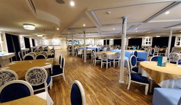 Dining area of a ship with tables and chairs.