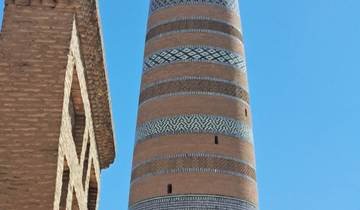 Tall minaret with intricate designs against a clear blue sky.